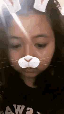 a girl wearing bunny ears on her head and a cat mask on her face .