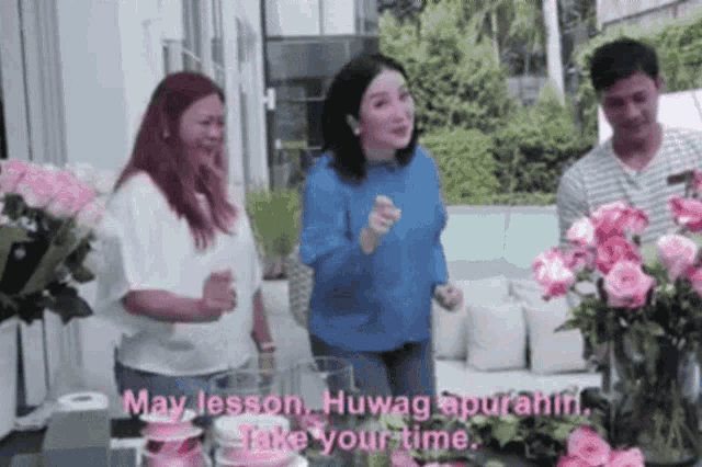 a group of people are standing around a table with flowers and a woman says may lesson