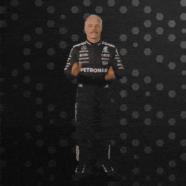 a man in a petronas uniform is clapping his hands in the air