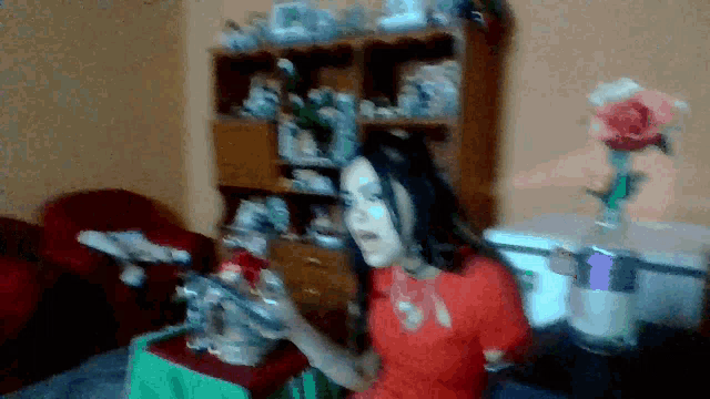 a woman in a red shirt is sitting in front of a bookshelf