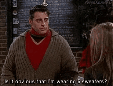 a man wearing a red sweater and a grey sweater is talking to a woman in a restaurant .