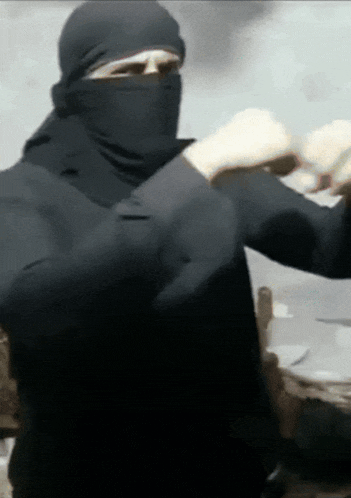 a woman wearing a black hijab is standing in front of a table with her arms outstretched