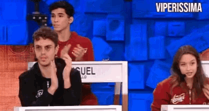 a group of people are sitting in front of a blue screen with the words viperissima on it .