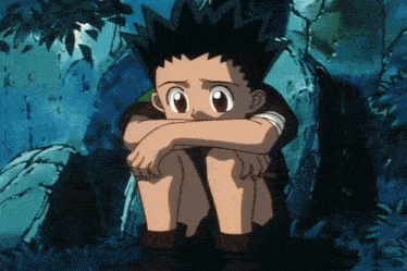 a young boy is sitting with his head on his knees