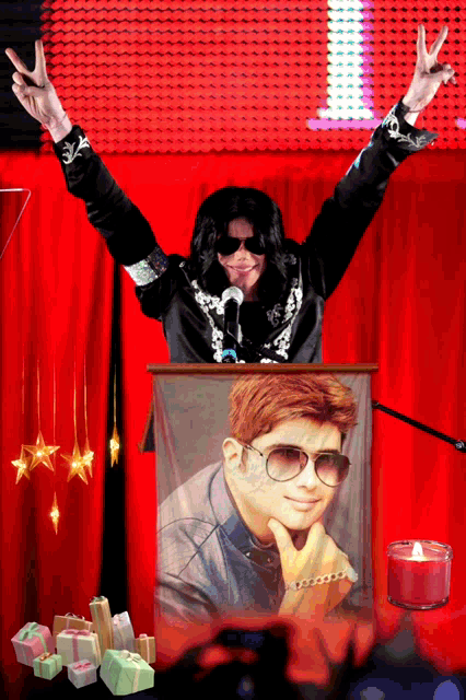 a man in a black jacket stands in front of a red curtain