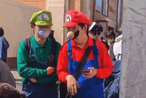 two people dressed as mario and luigi are standing next to each other .