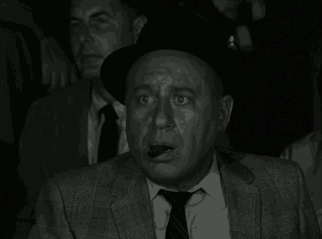 a black and white photo of a man in a suit and tie with a surprised look on his face