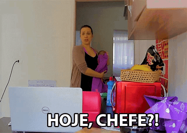 a woman holding a baby in front of a dell laptop that says hoje chefe