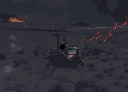 a helicopter is flying over a desert with a fire behind it