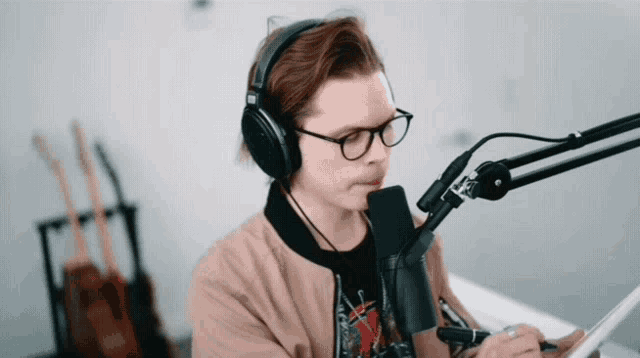 a man wearing headphones and glasses is sitting in front of a microphone