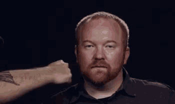 a man with a tattoo on his arm is getting a fist to the face .