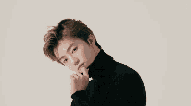 a close up of a young man wearing a black turtleneck sweater .