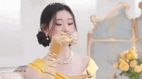 a woman in a princess dress is holding a cup of tea .