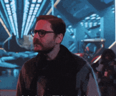 a man with glasses and a beard is standing in a room