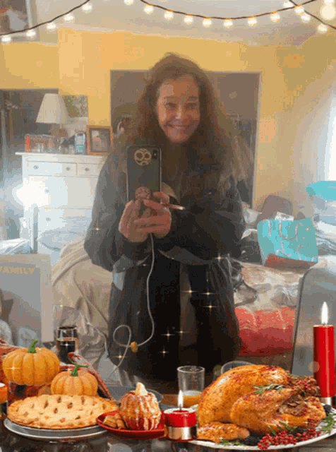 a woman is taking a picture of herself in front of a table with a turkey and pie
