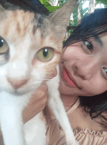 a woman holds a cat in her arms and the cat has green eyes