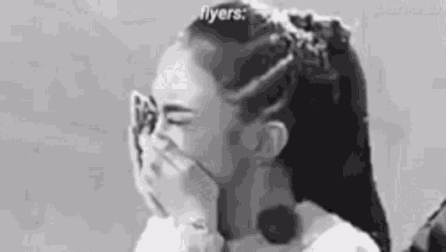 a black and white photo of a woman covering her mouth .