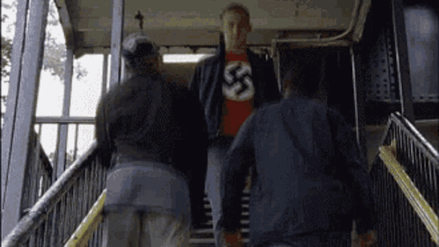 a man wearing a red shirt with a swastika on it is walking down stairs