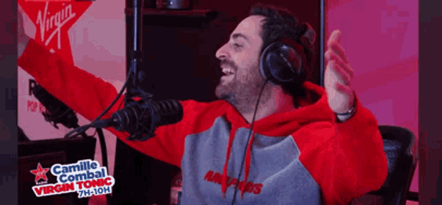 a man wearing headphones is singing into a microphone with a virgin flag behind him