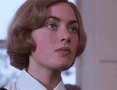 a close up of a woman 's face with red cheeks and a white shirt .