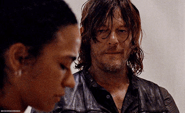 a man and a woman are looking at each other . the man is wearing a leather jacket .