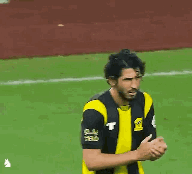 a man wearing a yellow and black jersey with the letter t on the front