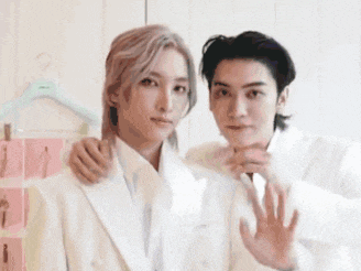 two young men in white suits are standing next to each other .