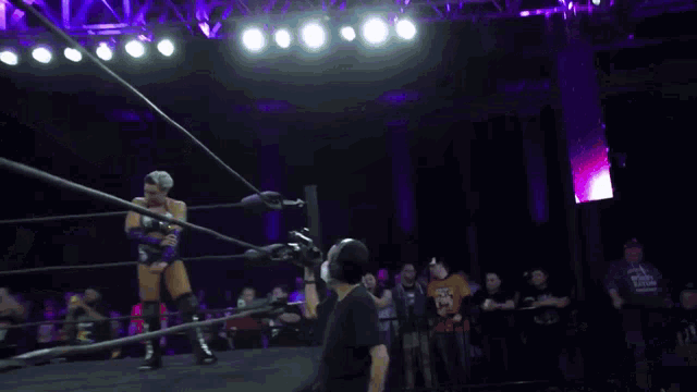 a woman in a pink dress is in a wrestling ring with her arms outstretched