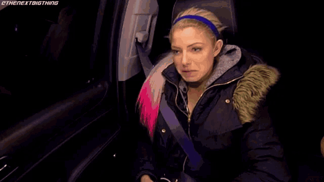 a woman is sitting in the back seat of a car with headphones on .
