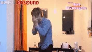a man is standing in a living room with joysound written on the wall
