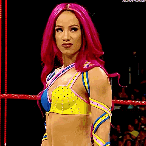 a woman with pink hair is standing in a ring wearing a colorful outfit .