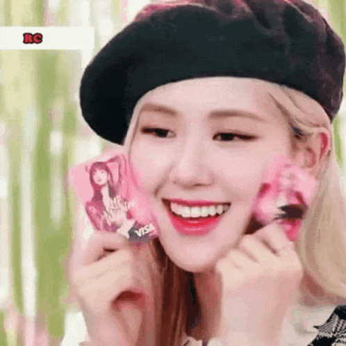 a woman wearing a black beret is holding a pink visa card