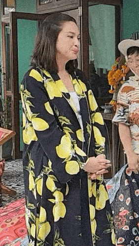 a woman wearing a black and yellow lemon print coat