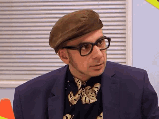 a man wearing glasses and a beret looks to his left