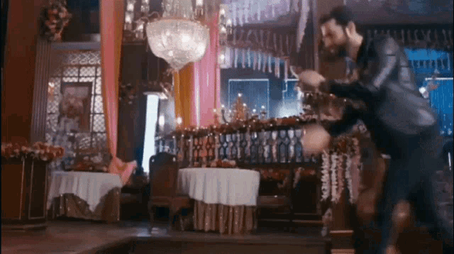 a man in a suit is dancing on a stage in a room .