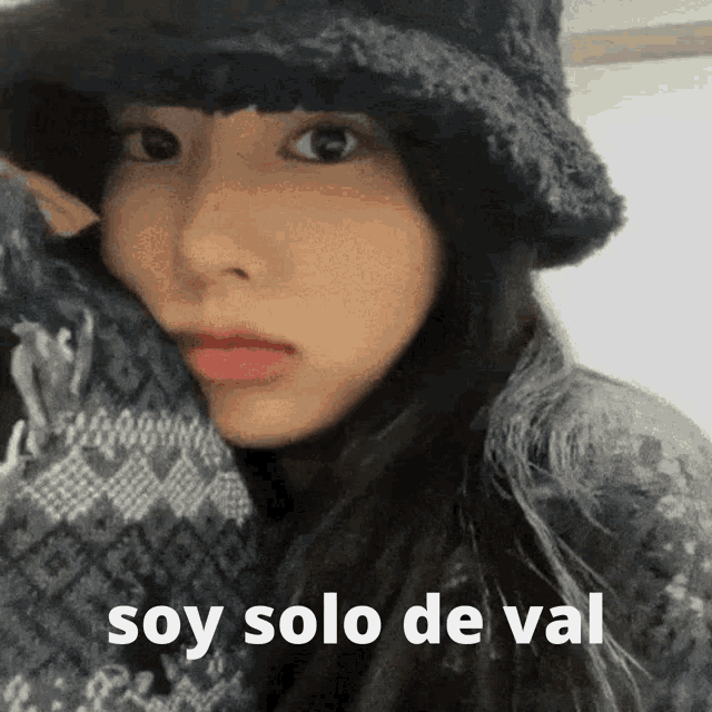 a woman wearing a hat and a scarf with the words soy solo de val on the bottom .