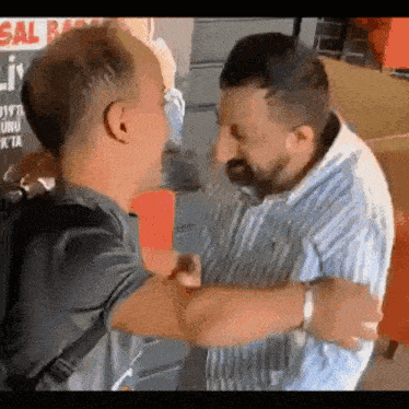 two men are standing next to each other and hugging each other .