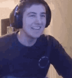 a young man wearing headphones and a black shirt is smiling and looking at the camera .