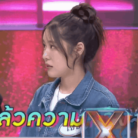 a woman wearing a denim jacket is standing in front of a sign that says x