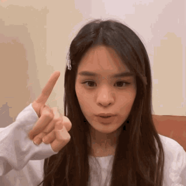 a woman with long hair is pointing her finger at something