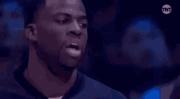 a man is smiling with his eyes closed and his mouth open in a dark room .