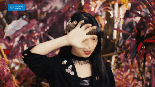 a woman covering her face in front of a sign that says up front works