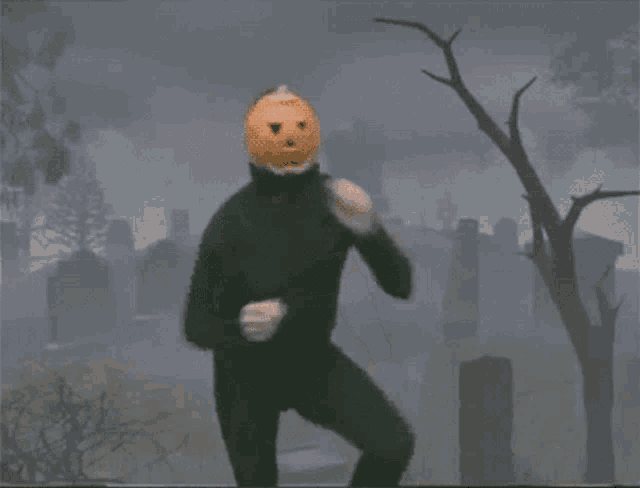 a person with a pumpkin on their head is dancing in a cemetery