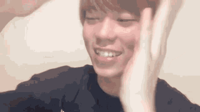 a young man is smiling and making a peace sign with his hands .