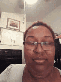 a woman wearing glasses and a white shirt smiles for the camera