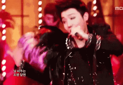 a man singing into a microphone with korean writing on the bottom of the screen