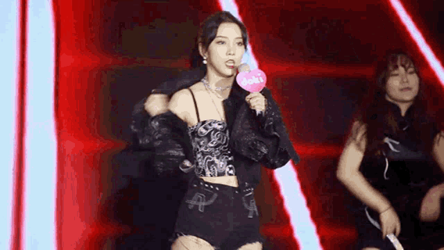 a woman singing into a microphone with a doki heart on it