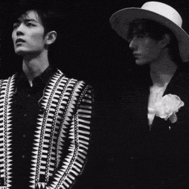 two men are standing next to each other one wearing a hat