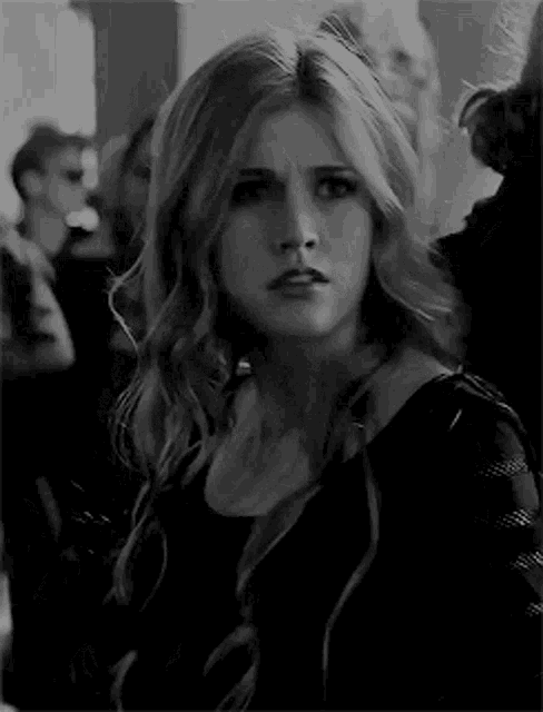 a black and white photo of a woman making a funny face in a crowd .