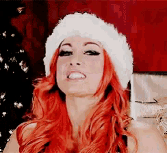 a woman with red hair wears a santa hat